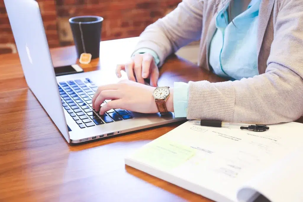 Employee typing on a laptop with notes